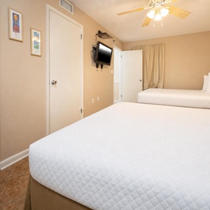 Soothing guest room features two queen beds, a wall-mounted TV, and warm tones, creating a welcoming retreat