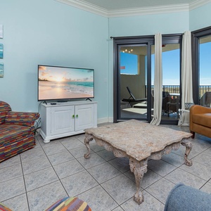Colorful patterned chairs and a rustic coffee table create a relaxed vibe in this living area with a view of the beach
