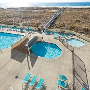 Inviting pool area features a large swimming pool, a kiddie pool, and lounge chairs, all with easy access to the beach