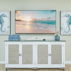 Enjoy the coastal charm of this living area, featuring seahorse artwork and a TV above a stylish console