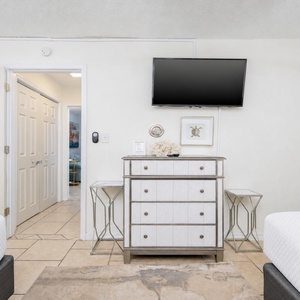 This inviting bedroom featuring two cozy queen beds, a stylish dresser, and a wall-mounted TV for entertainment