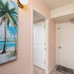 This welcoming entryway features a vibrant palm tree painting and a cozy doormat, setting a cheerful tone for your stay