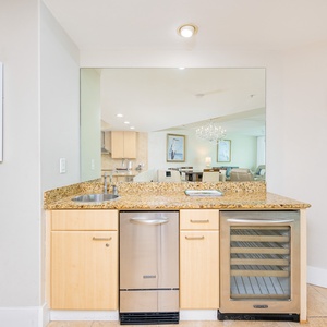 Stylish wet bar features granite countertops, stainless appliances, and a lovely view into the living area