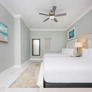 Relax in this guest bedroom featuring two comfortable queen beds with soft linens and a mounted TV