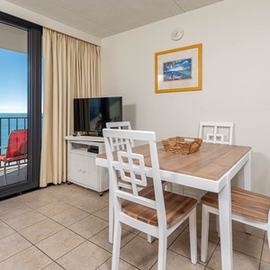 Enjoy dining with a stunning beachfront view from this inviting space featuring a cozy table and comfortable seating