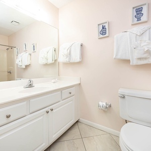 Bright guest bathroom featuring a spacious vanity, large mirror, and neatly arranged towels against soft pink walls