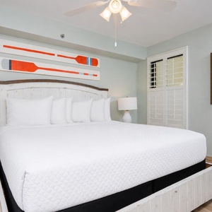 Inviting guest bedroom featuring a plush king bed, coastal decor, and natural light from the window shutters