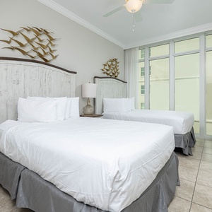 Relax in this guest bedroom featuring two comfortable queen beds, a TV, and large windows that invite natural light