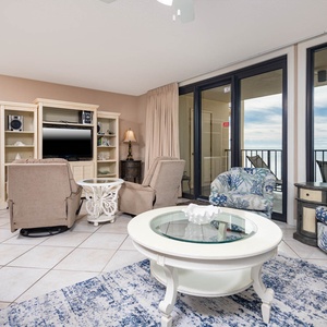 Living area featuring coastal decor, a TV, queen sofa-sleeper, and large windows showcasing serene waterfront views