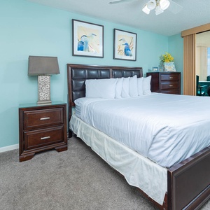 The serene master bedroom features a plush king bed, stylish nightstands, and a balcony with a view of the beach beyond