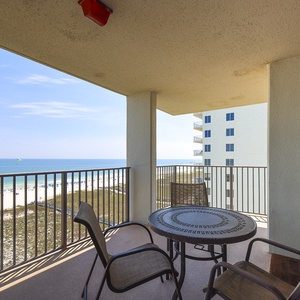 Balcony features a round table with chairs, offering a panoramic view of the beach and the tranquil gulf waters