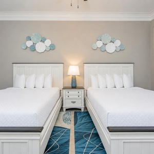 Rest in this inviting guest bedroom featuring two comfortable queen beds and stylish coastal decor