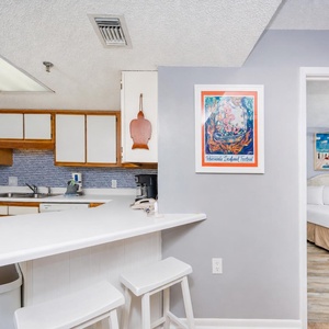 Kitchen with white cabinetry and all essential appliances, offering a view on the beach