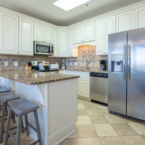 Modern kitchen featuring granite countertops, a breakfast bar, and seating at the breakfast bar with stylish gray stools