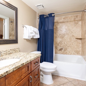 The bathroom features a granite countertop, a tub/shower combo with a navy curtain, and elegant tile accents throughout
