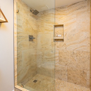 Experience rejuvenation in the spacious shower, surrounded by elegant tiles and cozy amenities for your comfort
