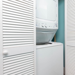 This laundry area features a stacked washer and dryer behind white louvered doors, perfect for convenience during your stay