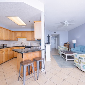 The modern kitchen features wooden cabinetry, a sleek black refrigerator, and a breakfast bar with stylish metal stools