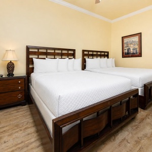 Calming guest bedroom featuring two comfortable queen beds and warm wood accents for a relaxing stay