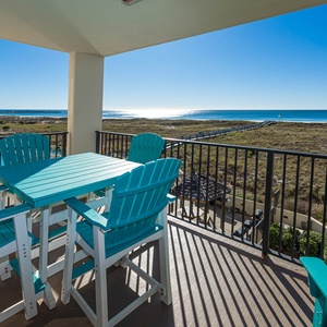 Balcony with turquoise seating offers a serene view of the beach and pool area, perfect for relaxing in the sun
