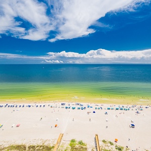 Enjoy breathtaking views from your balcony, where vibrant beach umbrellas dot the shoreline and invite relaxation