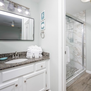 The master bath features a stylish granite countertop, a walk-in shower, and fresh towels for your convenience