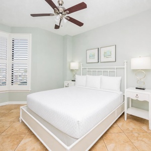 The guest bedroom features a comfortable white bed, elegant decor, and a charming view through the bay window