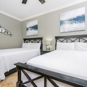 This guest bedroom features two comfortable queen beds, stylish black furnishings, and serene artwork for a relaxing stay