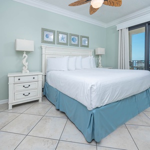 Serene master bedroom featuring a king bed, coastal decor, and beachfront balcony access