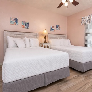 Sleep peacefully in this inviting guest room with two double beds, beach decor, and natural light from the window