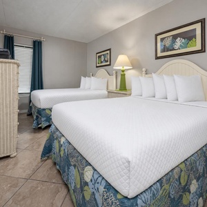 Guest bedroom featuring two double beds, a stylish lamp, and a TV, perfect for a relaxing getaway