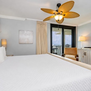 Relax in the master suite while the ceiling fan stirs gentle air and a shore view shines through sliding doors