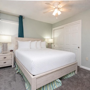 This cozy guest bedroom features soft teal accents, a plush queen bed, and a wall-mounted TV for your entertainment