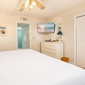 Soft white linens cover the queen bed in the guest suite as you unwind watching your favorite show on TV
