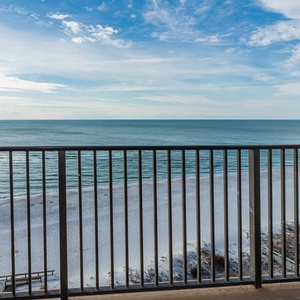 The balcony offers a serene view of the calm sea and white sand beach, perfect for relaxation and enjoying the scenery