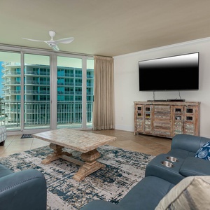 The living area features a large TV, a stylish coffee table, and a cozy seating arrangement with a beautiful view