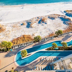 This beachfront balcony overlooks the pool and lazy river area with a waterslide and the beach just steps away