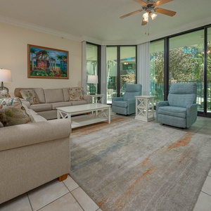 Relax in this airy living space, where sunlight dances through large windows, inviting you to unwind