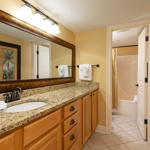 Granite countertop with elegant fixtures and decorative mirrors enhances the warm ambiance of the master bath