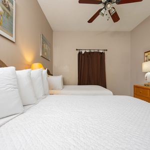 Rest in this inviting guest bedroom featuring two double beds, a TV, and warm lighting for a relaxing stay