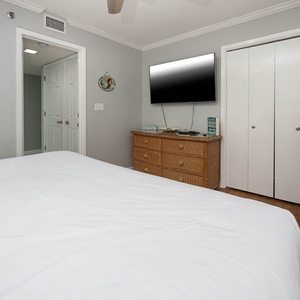 Guest bedroom featuring a large king bed, a wall-mounted TV, and a vibrant wave painting, creating a relaxing vibe