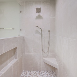 Experience a refreshing shower in this elegant master bathroom featuring a spacious walk-in design and stylish tile