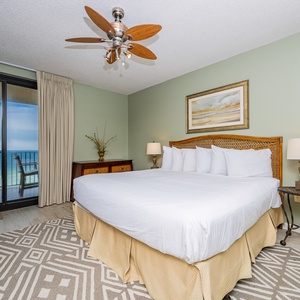 Relax in the master bedroom featuring a king bed, decorative rug, and beachfront balcony access