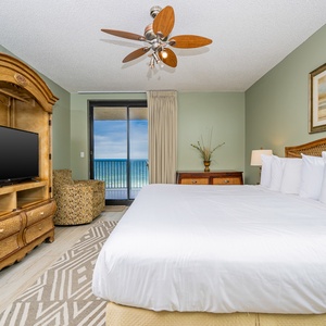 Spacious master suite featuring a king bed, cozy seating, and a stunning beach view through sliding glass doors