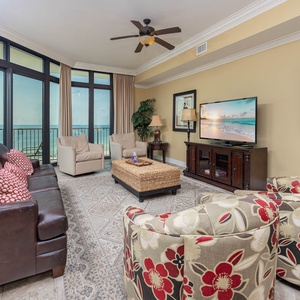 Living room featuring a cozy leather sofa with queen sleeper, floral chairs, and large windows showcasing beautiful views