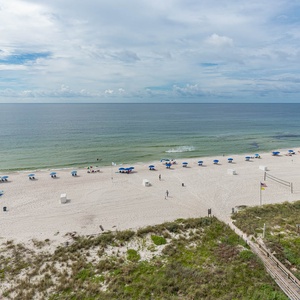 This stunning view showcases a pristine beach with blue umbrellas and soft white sand, perfect for relaxation and fun