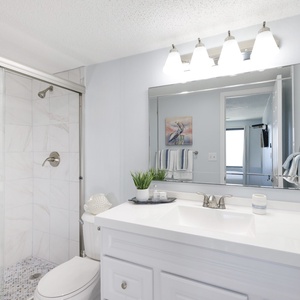 This bathroom features a sleek shower, bright lighting, and soft blue accents for a refreshing retreat