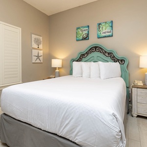 Iinviting guest bedroom featuring a comfortable queen bed, coastal decor, and soft lighting for a restful stay
