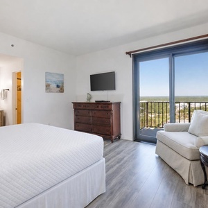 Master bedroom featuring a cozy king bed, flat-screen TV, and a balcony with a beautiful view of the landscape