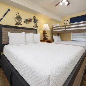 Guest room featuring a queen bed and a cozy twin over full bunk bed, accented with nautical-themed wall art and warm lighting